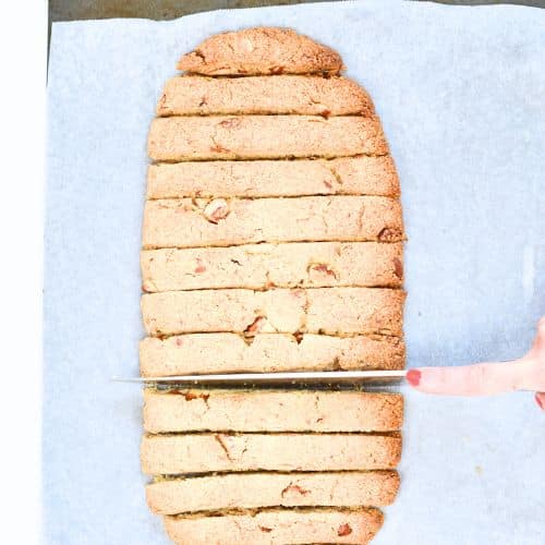 Slicing Keto Almond Flour Biscotti on a baking sheet.