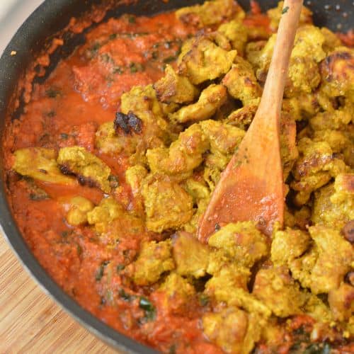 Mixing chicken in Indian spices.