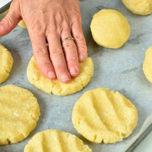 Flattening Keto Coconut Cookies on a baking sheet.