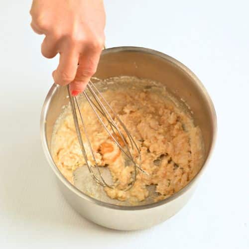 Stirring the Keto Oatmeal to thicken it in a saucepan.