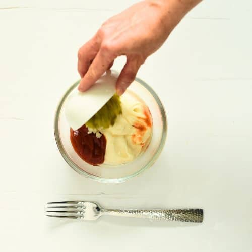 Pouring the Keto Thousand Island Dressing ingredients in a bowl.