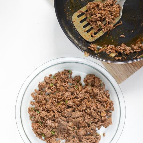 Placing cooked meat at the bottom of a pan for the Taco Egg Bake